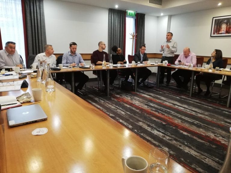 A management team seated around a U-shaped boardroom table during a Plan Grow Do session