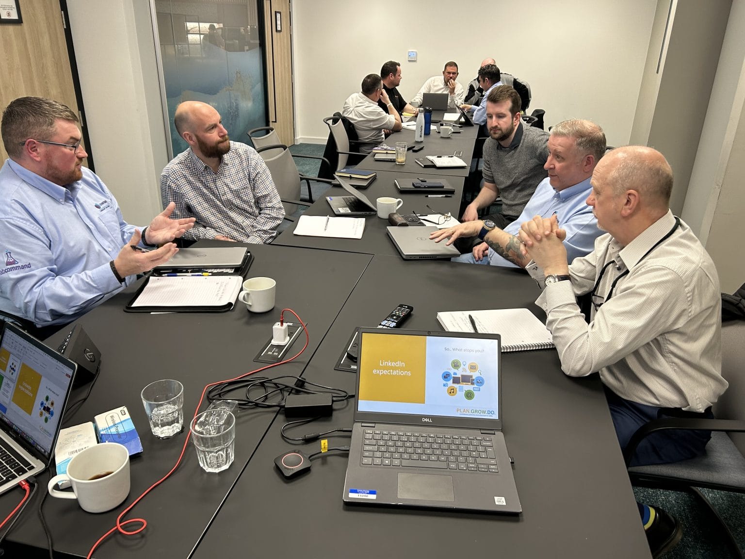 A leadership team in discussion around a boardroom table with Plan Grow Do