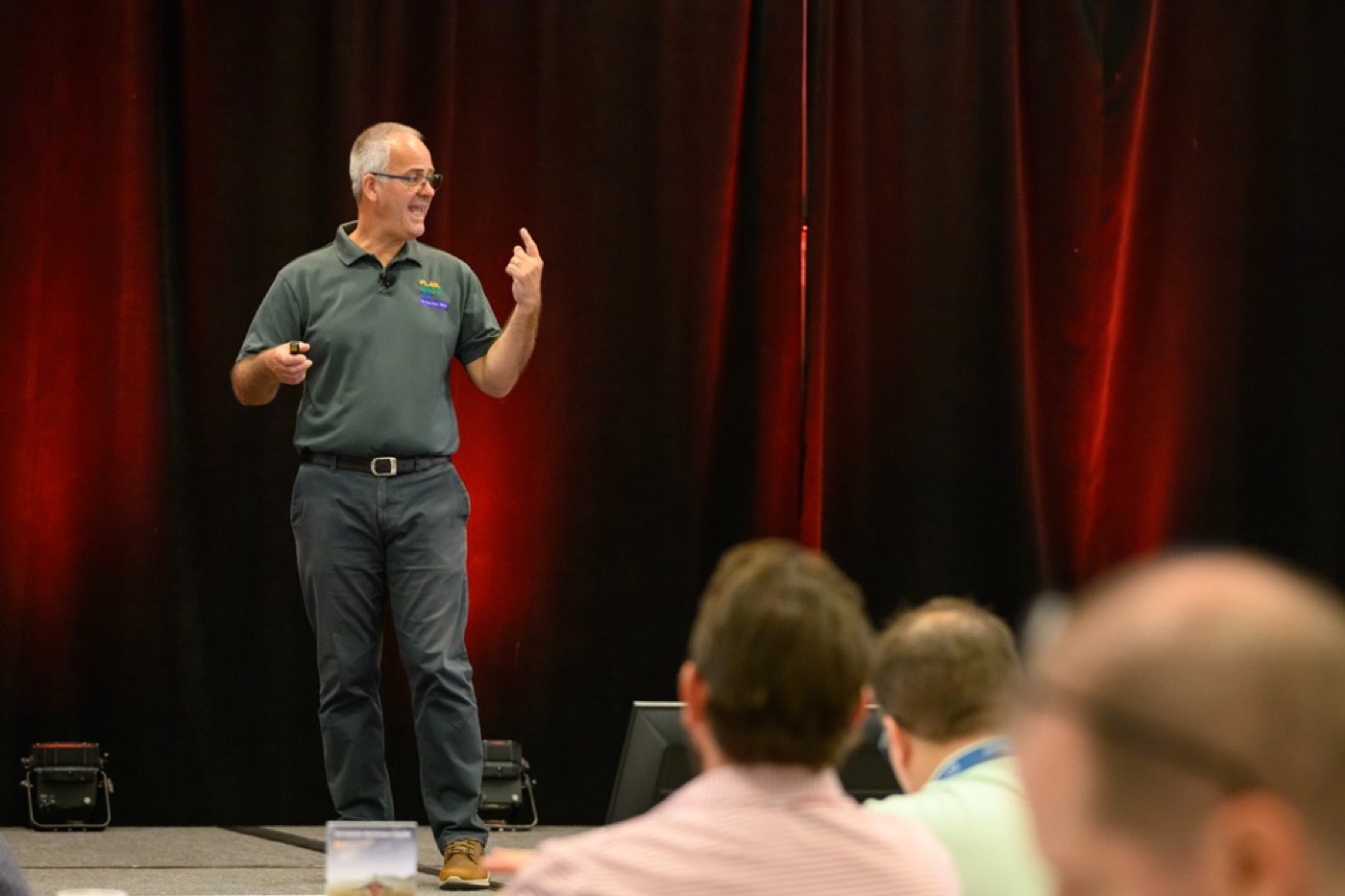 Steve Knapp presenting on stage in a Plan Grow Do shirt